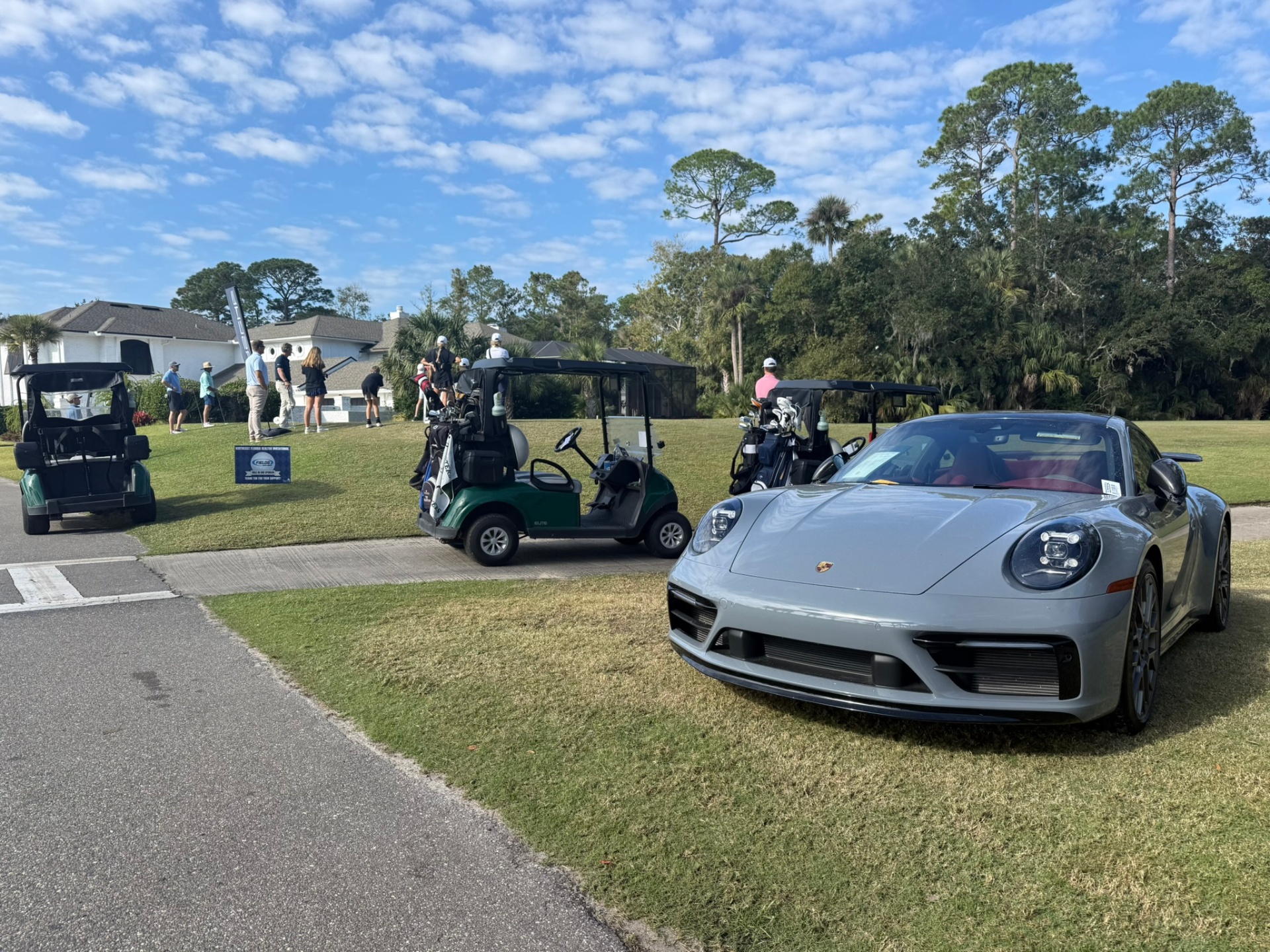 Porsche on display next to golf carts at the tee